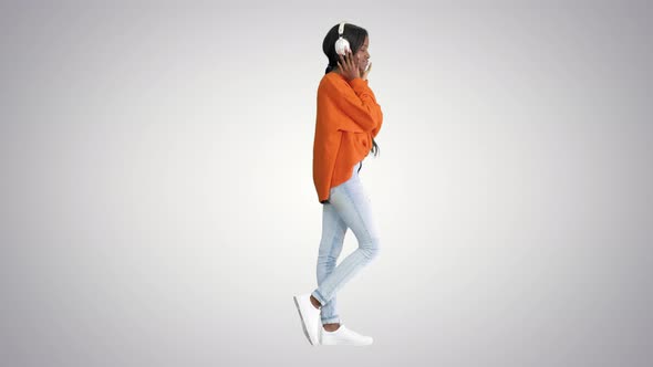 Young African American Woman with Headphones Listening and Grooving To Music on Gradient Background. alt