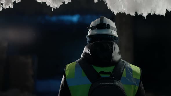 Back View Caucasian Man Standing in Snow Cave Touching Frost Looking Around alt