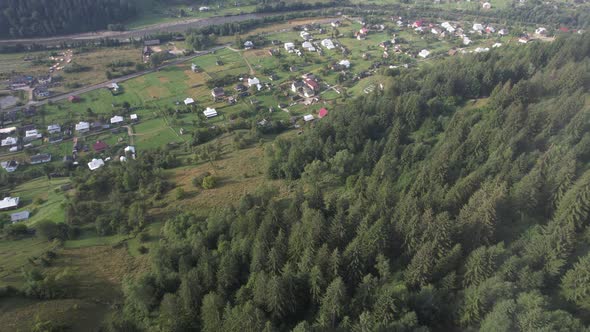 Drone Flying Over a Village in a Mountainous Area with Low Clouds in the Lowlands