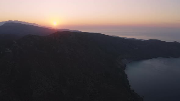 Aerial view of Sunrise above Coast line and Mountain. Flying over sea in the morning alt