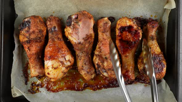 Chicken leg cooking process. Chef flips fried chicken legs, top view alt