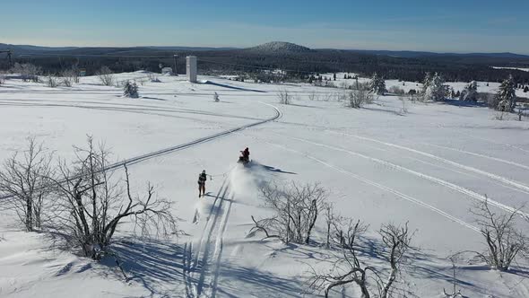 Aerial View of Winter Fun, Snow Scooter Towing Skier on Sunny Day, Drone Shot alt