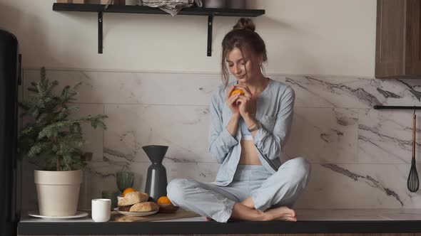 Woman Enjoying Orange Smell in Kitchen.