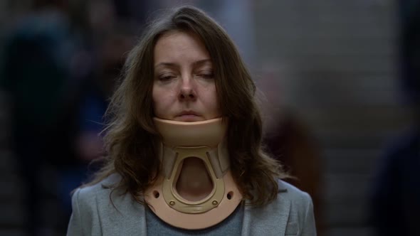 Tired Woman with Osteochondrosis and Neck Ache Is Wearing Cervical Collar, Standing on Street in Big alt