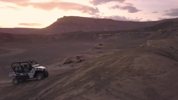 Panning view of OHV driving over dirt hill in the desert alt