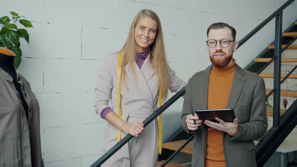 Slow Motion Portrait of Sewing Business Owners Standing in Studio Smiling alt
