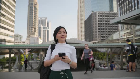 Portrait of asian woman with earphone listening music and using smartphone