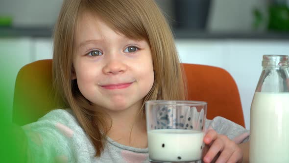 Child Looks at Camera and Has Breakfast with Milk and Bread