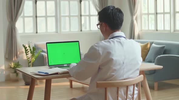 Man Doctor Video Call On Laptop Computer With Green Screen And Talking To Patient Online alt