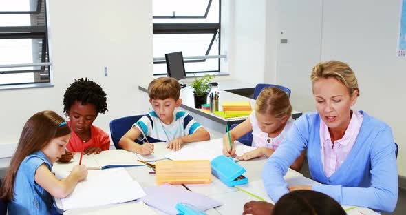 Teacher helping kids with their homework in classroom alt