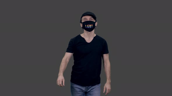 Walking gay person in black t-shirt and anti covid lgbt mask, Alpha in