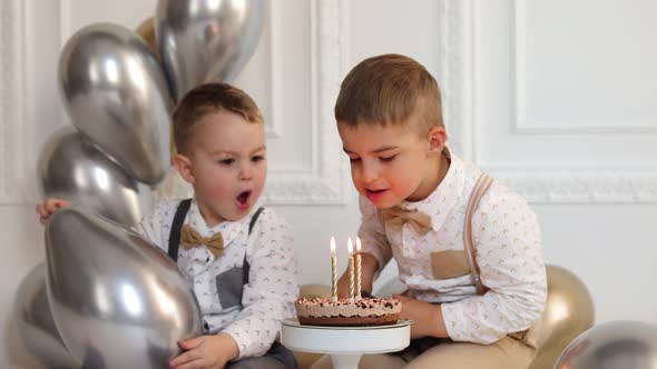 Kids blowing candles on the birthday cake.