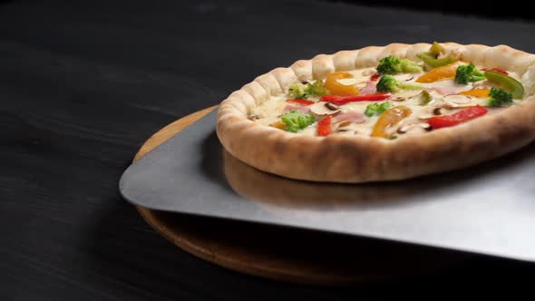 Pizza From a Steel Shovel is Placed on a Wooden Board on a Dark Background