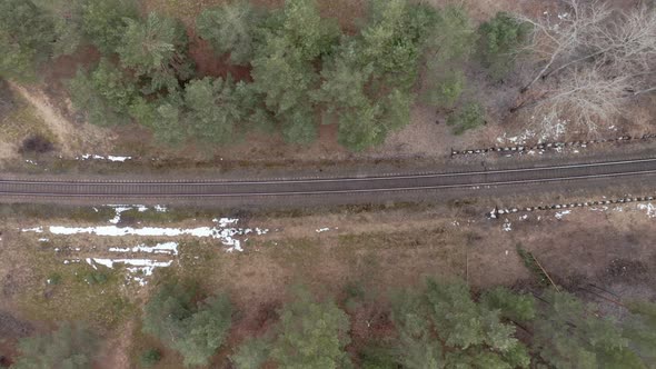 AERIAL: Railway in a Forest on a Gloomy Cloudy Day in Springtime