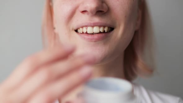 Young Smiling Woman Applying Cream on Her Face Close Up