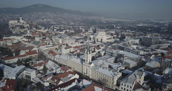 Wide aerial shot of Nitra town with Castle and mountains in background, Winter, Slovakia alt