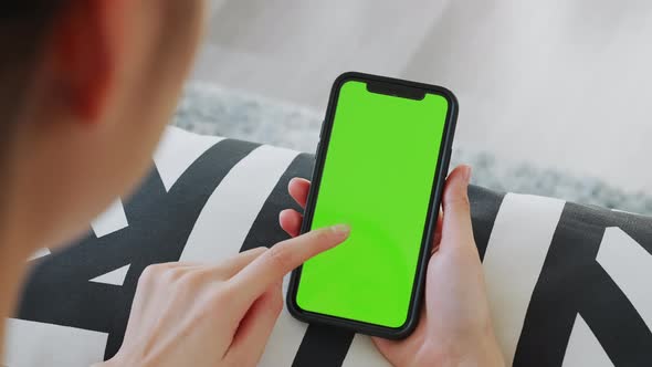 woman holding in hands a mock up smartphone with green screen for internet online. alt