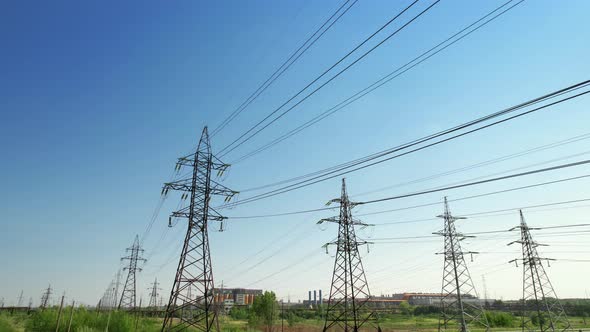 Four Power Energy Lines of Highvoltage Transmission Pylons with Industrial Background and Clear Blue