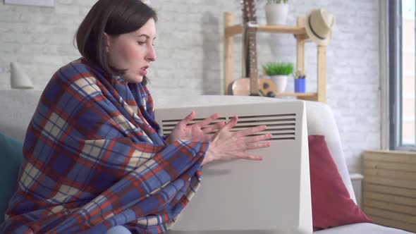 Young Woman Freezes in the Living Room and Heats Herself Next To an Electric Heater alt