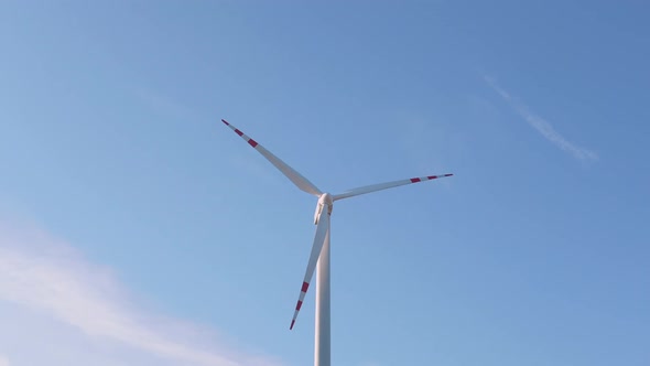 Close Up of a Wind Turbine Spinning on Light Blue Sky on Background alt