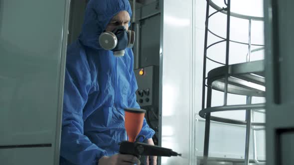 Master painter paints chair blanks in a special chamber in a furniture factory