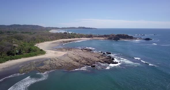 Aerial drone view of the beach, rocks and tide pools in Playa Palada, Guiones, Nosara, Costa Rica. alt