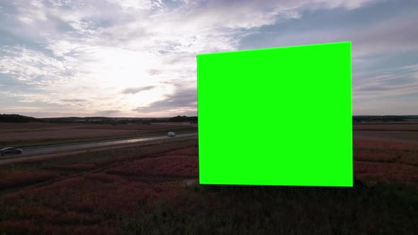 Aerial Drone Footage of Big Billboard with Green Screen near Busy Highway or Motorway at Sunset