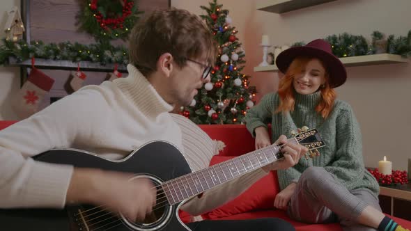 Caucasian couple having fun and singing on decorated cozy living on christmas season. alt