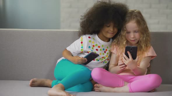 Afro-American Girl Hugging Her Caucasian Cousin and Taking Selfie on Cellphone alt