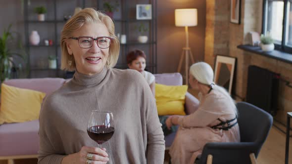 Portrait of Mature Blonde Woman with Glass of Red Wine alt