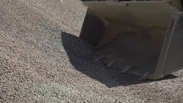Side View of Tractor Bucket Downloading Crushed Stone Outdoors on Factory. Process of Material alt