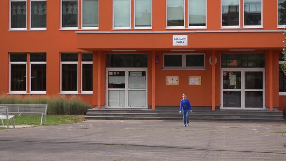 A Young Boy Walks Away From the Elementary School alt