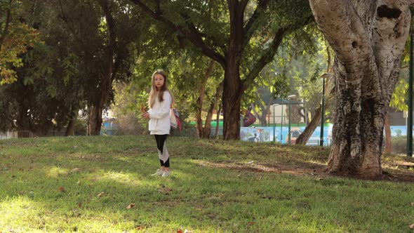 Cute Girl Collecting Autumn Leaves in Park