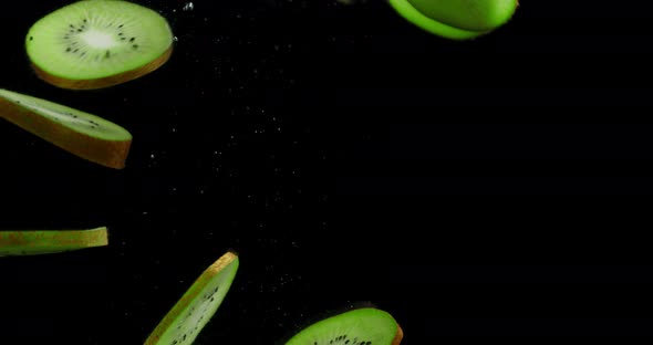 Round Slices of Ripe Kiwi Fall Under Water with Air Bubbles. 
