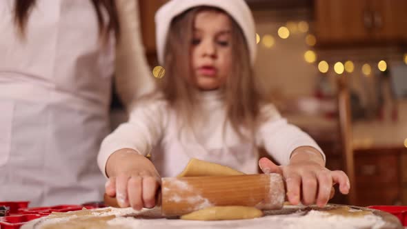 Daughter and Mom Using Rolling Pin for Making Gingerbread alt