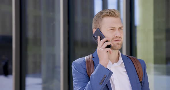 Businessman standing in front of glass window using mobile phone alt
