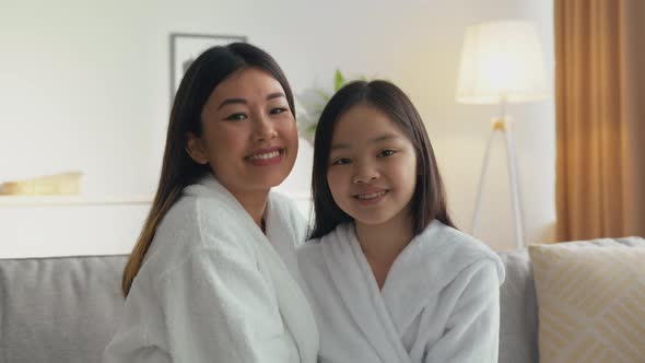 Portrait of Happy Asian Mother and Daughter Smiling to Camera and Rubbing Noses Sitting Together at