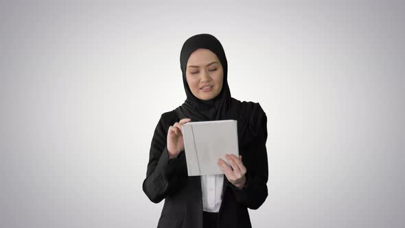 Cute Arabian Businesswoman Using Tablet Computer While Walking on Gradient Background alt