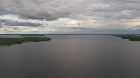 Quadrocopter flies over a lake surrounded by forest