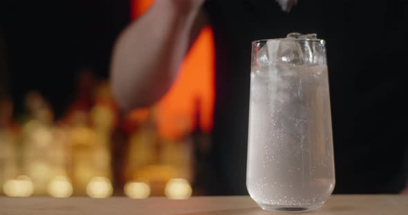 Bartender Adds Ice Cubes to the Glass with Refreshment Beverage in Slow Motion Making the Limonade alt