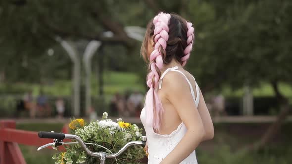 Woman in White Dress Looking at Camera While Riding in Park