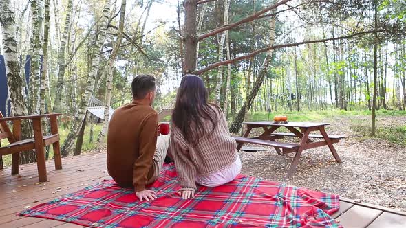 Young Couple Sitting on the Terracein the Autumn Forest alt
