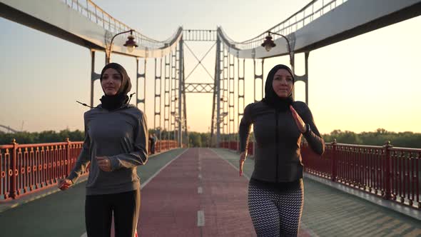 Fit Arab Women in Hijabs Running Fast on Bridge