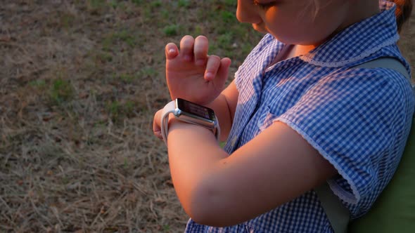 Child schooler using smartwatch outdoor park. Kid talking on vdeo call with parents on smartwatches