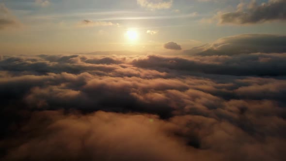 Aerial view: Flying Over Clouds on Sun Rise in Mountains.