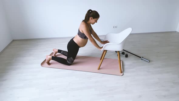 Slow motion shot of pregnant woman during exercise on mat and chair