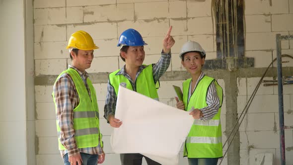 Group of Asian engineer or Young Female Architect put on a helmet for safety and talk with a contrac