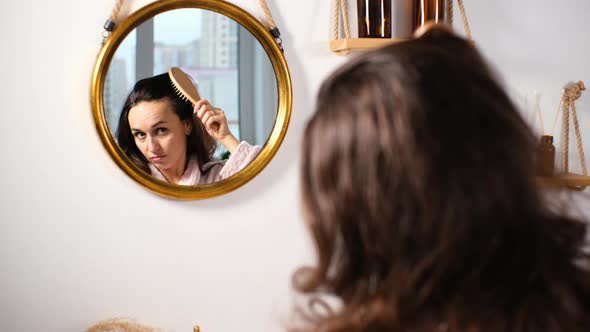 Woman Combing Her Hair in Front of Bathtub Mirror alt