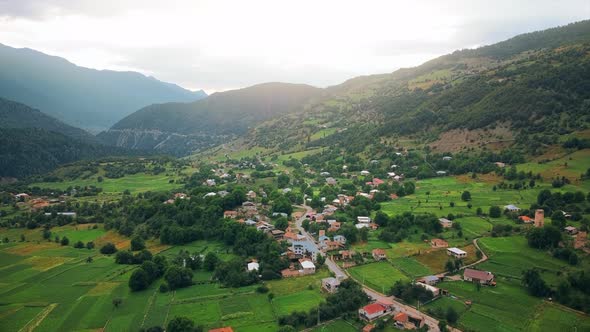 Aerial drone view of a village in Georgia. Valley, buildings, mountains and hills slopes covered wit alt