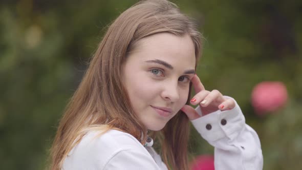 Portrait of Pretty Carefree Young Woman with Different Colored Eyes Looking at Camera Indoors alt